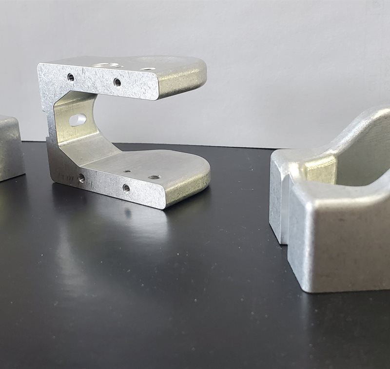 Three machined aluminum brackets on a workbench