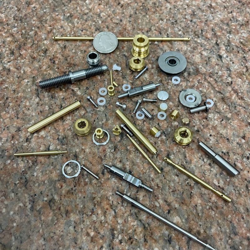 Tiny precision-machined parts with a coin for scale