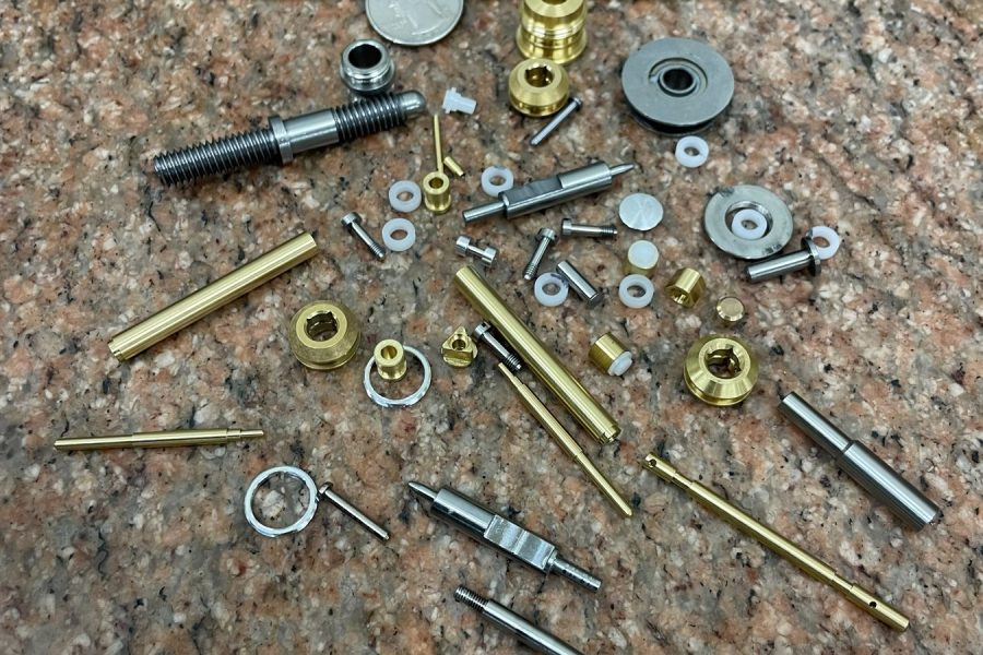 Tiny precision-machined parts with a coin for scale